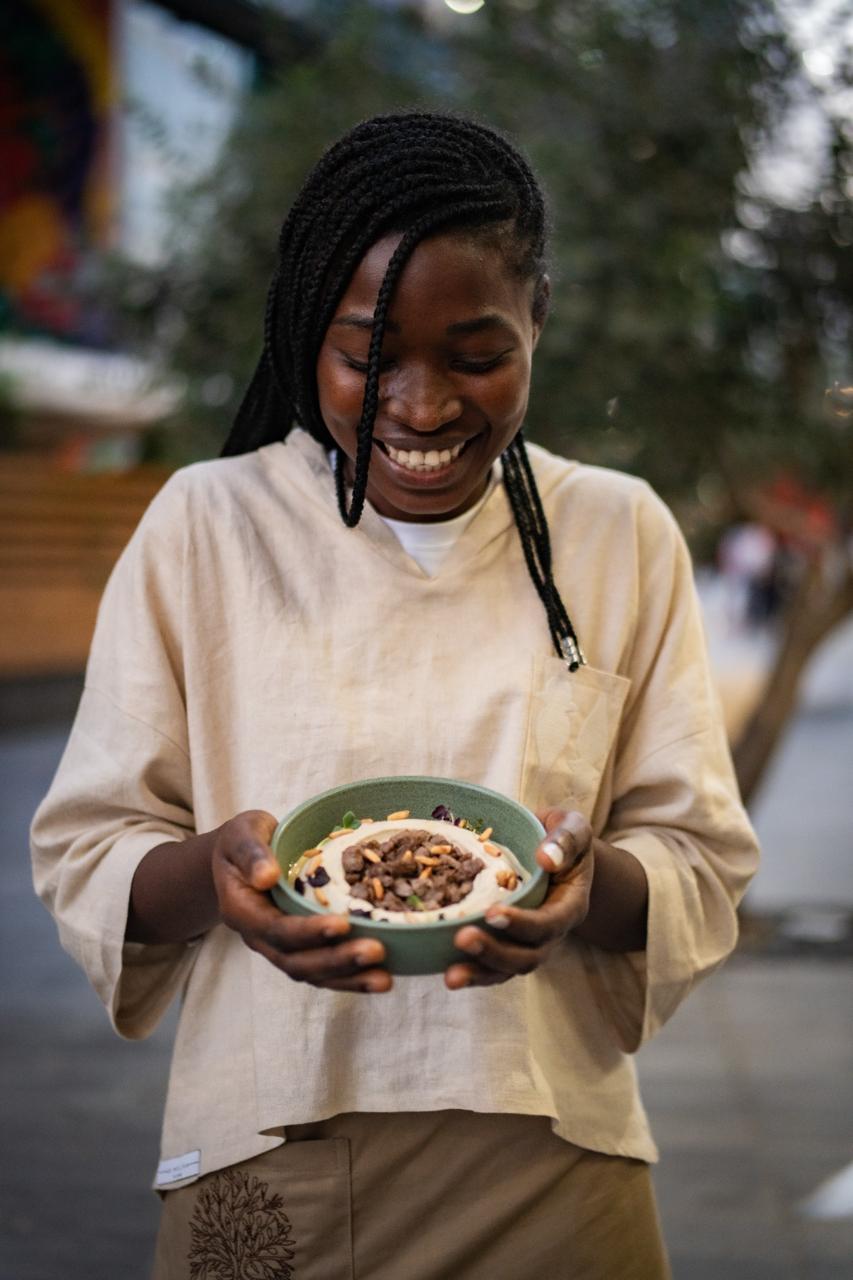 A smiling SOYL team member holding a freshly prepared dish